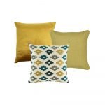 An image of a one gold cushion cover, on green cushion cover and one cushion cover with a cross pattern.