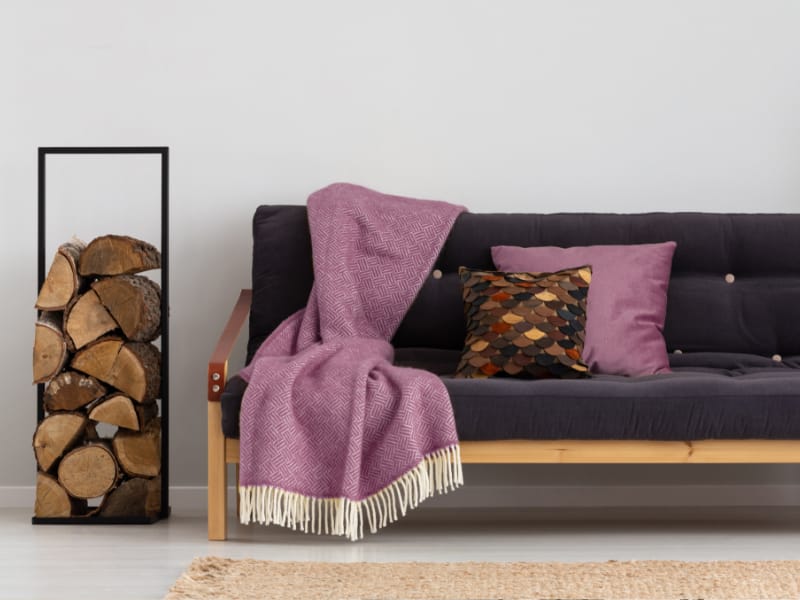 Minimalist living room with mauve cushions styled on a lounge with a matching throw