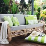 Lime green outdoor cushions with a white knit throw rug on an outdoor lounge and green and white striped floor cushion