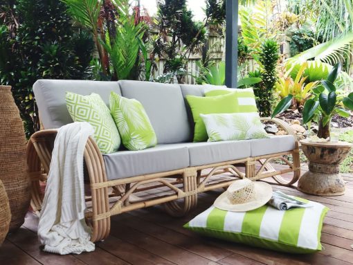 Lime green outdoor cushions with a white knit throw rug on an outdoor lounge and green and white striped floor cushion