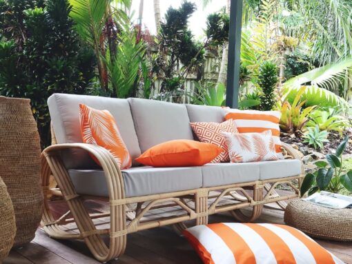 Orange outdoor cushion covers on a light grey three seater outdoor setting with a striped orange and white floor cushion