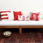 Red outdoor cushions mixed with beige outdoor cushions sitting on a white outdoor lounge setting
