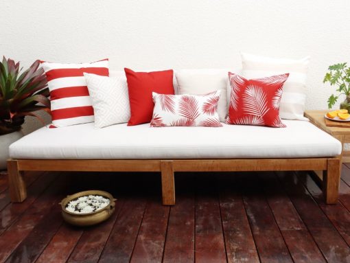 Red outdoor cushions mixed with beige outdoor cushions sitting on a white outdoor lounge setting