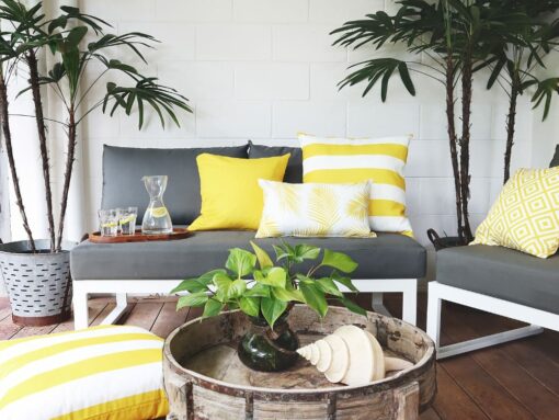 Bright yellow outdoor cushions on a dark grey outdoor 2 seater chair with a yellow striped outdoor floor cushion