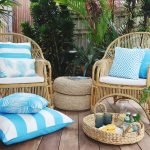 Bright blue outdoor cushions on two outdoor wicker chairs with an outdoor floor cushion on the ground