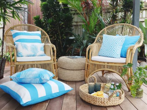 Bright blue outdoor cushions on two outdoor wicker chairs with an outdoor floor cushion on the ground