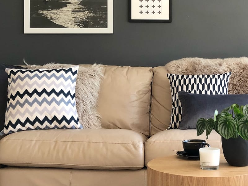Several chevron cushions are positioned on a couch in black, white and grey tones.