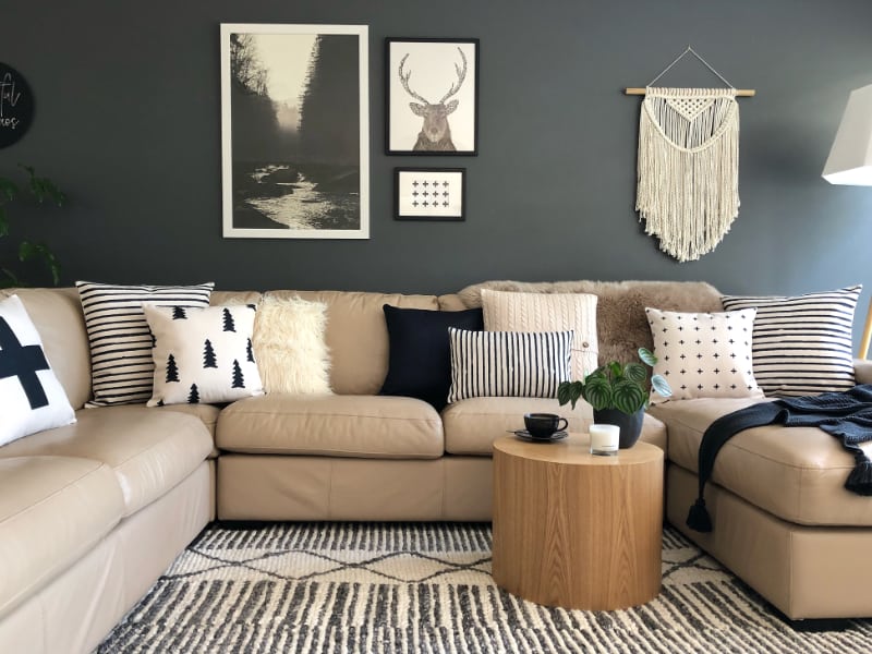 A set of Scandi Cushions in black and white colours lay arranged on a light coloured lounge with Scandinavian wall art in the background.