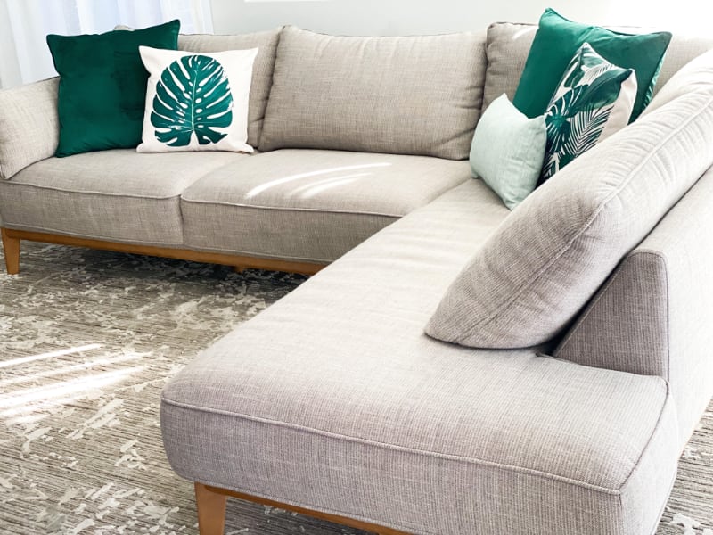 A stylish display of green leaf cushions on a light grey lounge