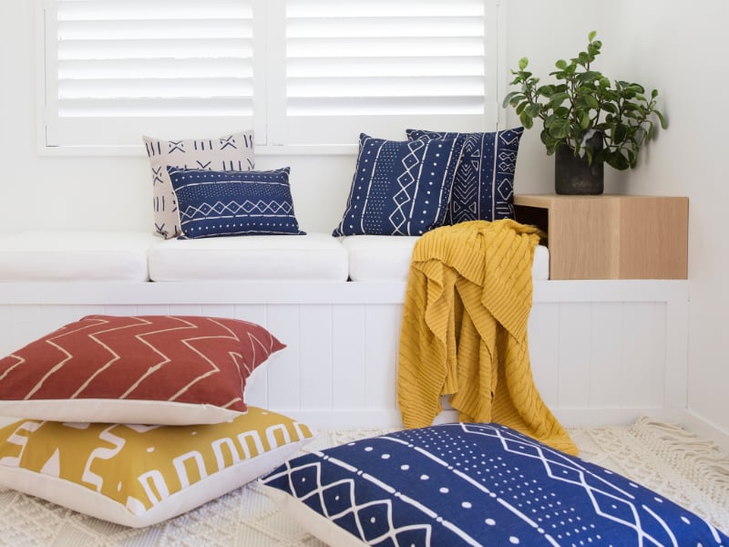 Vibrant blue red and yellow mudcloth cushions in a white sitting room