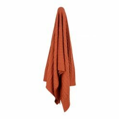 An image of a knitted throw blanket in red orange colour