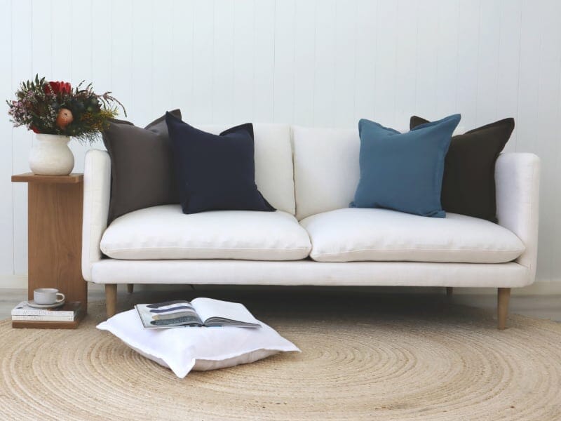 Large blue grey and charcoal designs on a blank white sofa with native flowers nearby