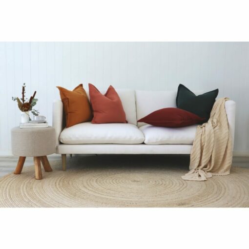 Mustard, pink and maroon linen cushions on a white sofa against a white wall