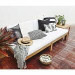 Black outdoor cushions in stripe, diamond and floral patterns on top of white wooden daybed.