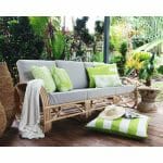 Green outdoor cushions in stripe, block, diamond and floral patterns on top of grey rattan sofa.