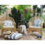 Grey outdoor cushions in stripe, diamond and floral patterns on top of rattan lounge chairs.