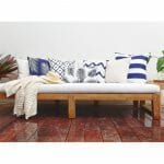 Navy outdoor cushions in stripe, chevron, diamond and floral patterns on top of white wooden daybed.