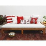 Red outdoor cushions in stripe, diamond and floral patterns on top of white daybed.