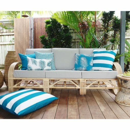 Teal outdoor cushion covers in diamond, floral stripe patterns on top of rattan sofa