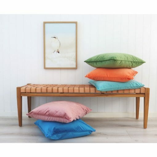 Bright velvet cushions on a bench seat with coastal wall art