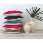A stack of bold velvet linen cushions against a white wall