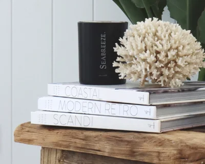 A black candle jar sitting on a pile of books.