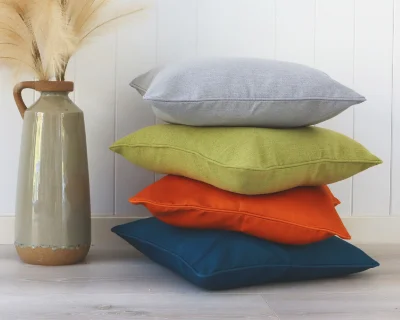 Four cheap cushions have been styled against a white wall and vase.