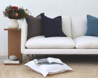 A light sofa with two bold linen cushions arranged on it and the floor.