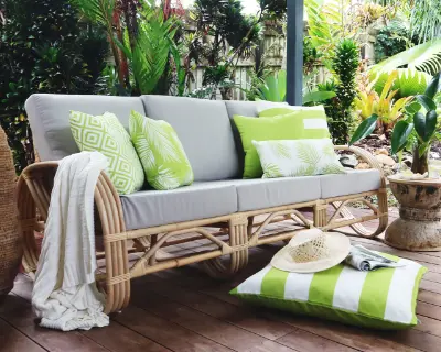 A set of lime green outdoor cushion covers styled on a grey sofa in a lush garden setting.