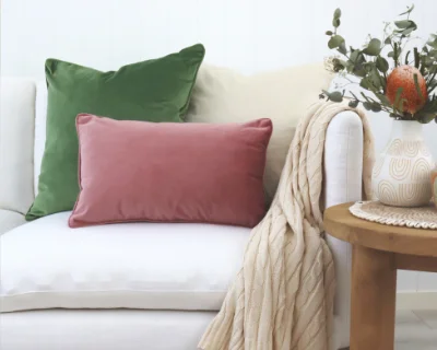 A pink coloured rectangular cushion styled upon a chair.