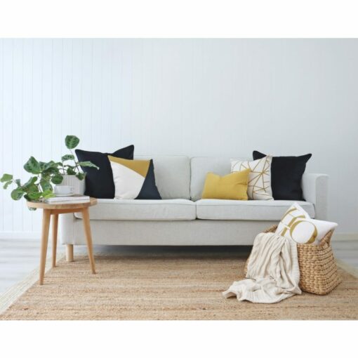 Neutral coloured living room with table plant, beige knit throw and gold and navy cushions