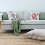 Australian botanical cushions paired with sage cushions on a neutral sofa with a sage throw