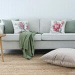 Australian botanical cushions paired with sage cushions on a neutral sofa with a sage throw