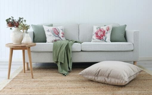 Australian botanical cushions paired with sage cushions on a neutral sofa with a sage throw