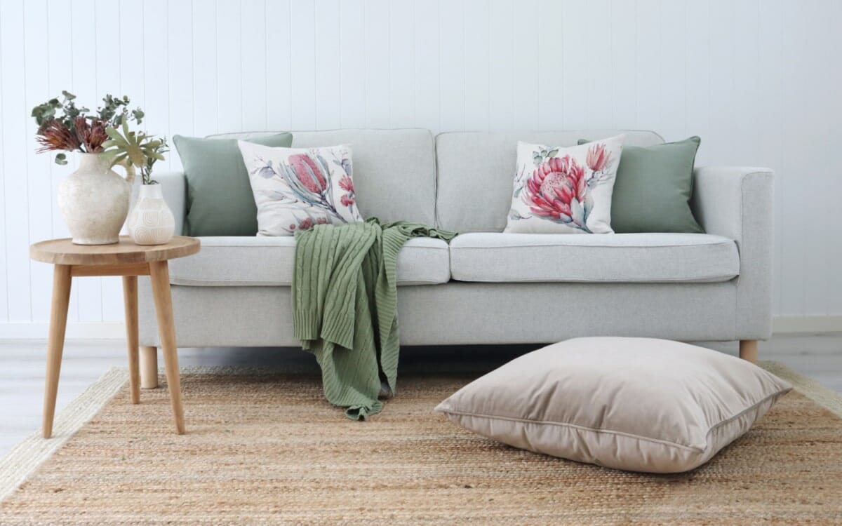 Australian Botanical cushions styled on a neutral sofa with a sage throw blanket