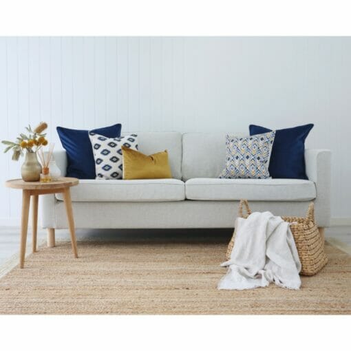 Neutral-coloured living room with wooden accents and gold and navy cushions