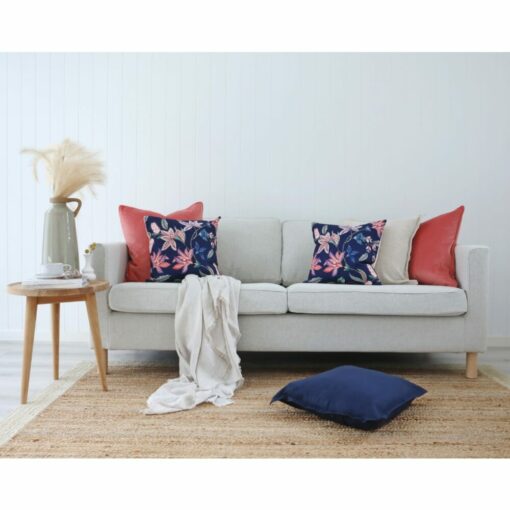 Light coloured sofa with, woven rug, wooden table, off-white throw and coral and navy cushions with floral prints