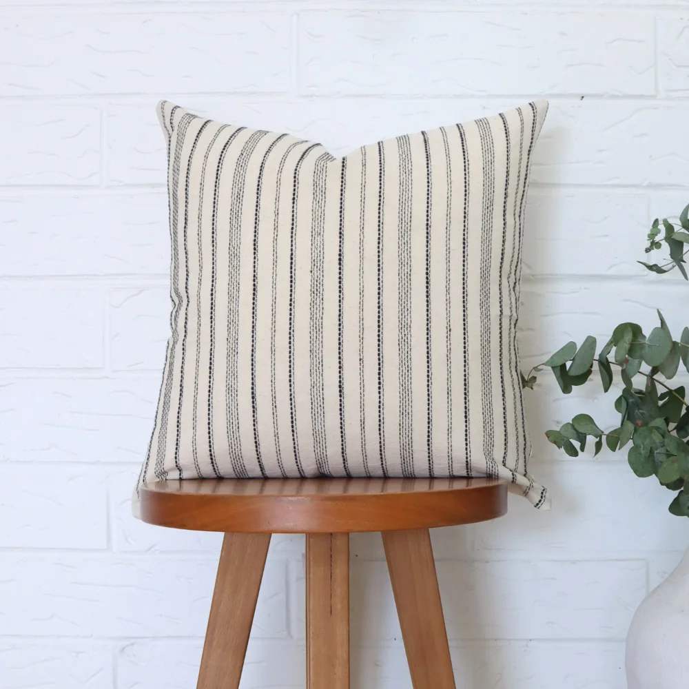A 45x45 cushion cover sits on top of a wooden stool.