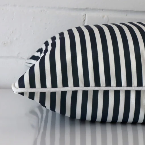 Outdoor blue cushion laying on its side. The striped design and its square size are visible.