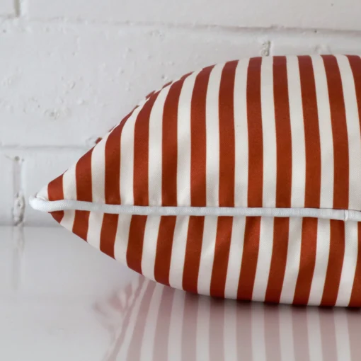 Side edge of striped square cushion. The outdoor material and terracotta colour can be seen from this lateral viewpoint.