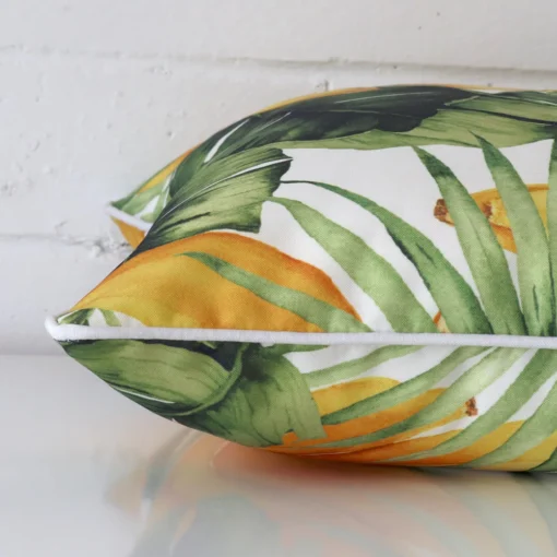 The edge of this outdoor square cushion is shown. The shot shows the banana tropical design and the front and rear panels.