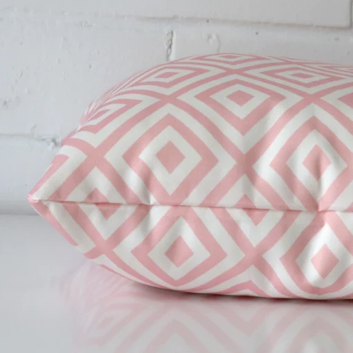 Outdoor pink cushion laying on its side. The geometric design and its square size are visible.