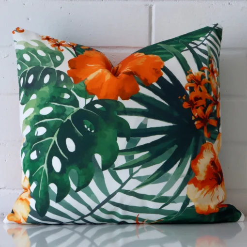 Orange tropical cushion cover sits against a white wall. It is constructed from a superior looking outdoor material and has square dimensions.