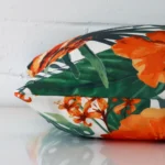 A sideways perspective of this tropical outdoor cushion. The positioning shows the border of the square shape and the orange colour.