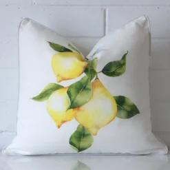 Square lemons cushion cover in sitting upright in front of a brick wall. It has been made from a quality outdoor material.