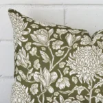 The corner of this linen rectangle cushion cover is shown close up. The floral design and green colour is shown in greater detail.