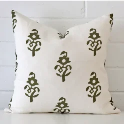 Square patterned cushion cover in olive green colour sitting upright in front of a brick wall. It has been made from a quality linen material.
