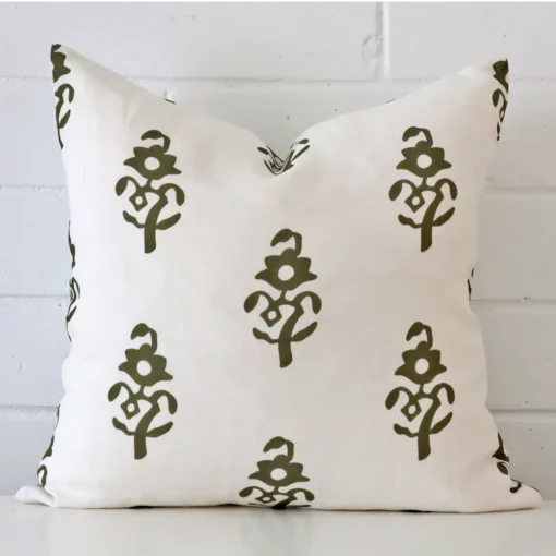 Square patterned cushion cover in olive green colour sitting upright in front of a brick wall. It has been made from a quality linen material.