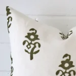 Corner section image showing features of square olive green cushion that has a patterned motif on its linen fabric.