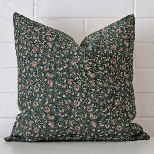 Floral cushion cover sits against a white wall. It is constructed from a superior looking designer material and has square dimensions.